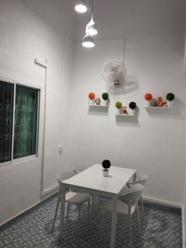 a white dining room with a white table and chairs at Batu Pahat Taman Banang Homestay in Batu Pahat