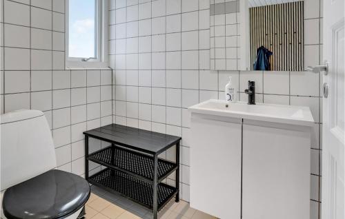 a white tiled bathroom with a sink and a toilet at Beautiful Home In Juelsminde With Sauna, Wifi And Private Swimming Pool in Sønderby