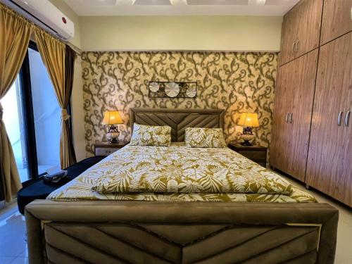 The Realtors Inn 1 BDR Apartment DHA 2 في اسلام اباد: غرفة نوم بسرير كبير فيها مصباحين