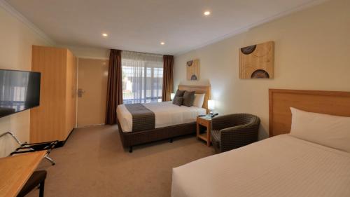 a hotel room with two beds and a television at New Crossing Place Motel in Seymour