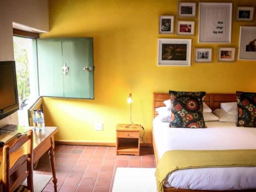 a bedroom with a bed and a desk and a television at The Oil Mill Guesthouse in Swellendam