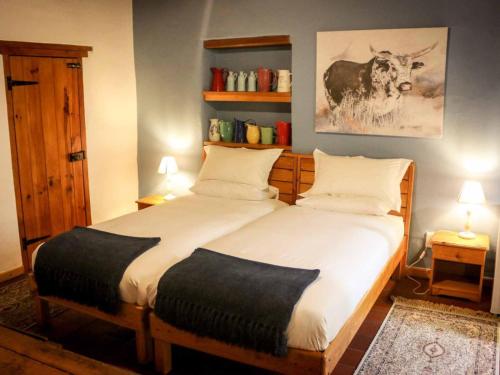 a bedroom with a large bed with a cow on the wall at The Oil Mill Guesthouse in Swellendam