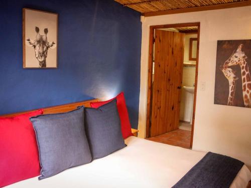 a bedroom with a bed and a giraffe picture on the wall at The Oil Mill Guesthouse in Swellendam