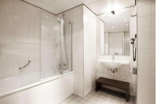 a white bathroom with a sink and a shower at NH Amersfoort in Amersfoort