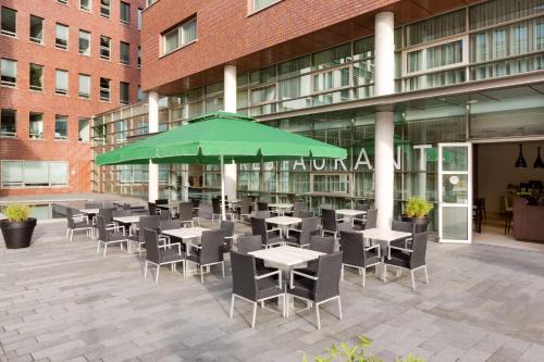 a cafeteria with tables and chairs and a green umbrella at NH Amersfoort in Amersfoort