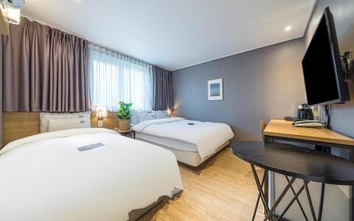 a hotel room with two beds and a desk at YAJA Hotel Tongyeong Ferry Terminal Branch in Tongyeong