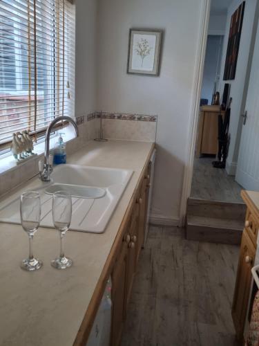 a kitchen with two wine glasses on a counter at Cottage 5 minutes walk to river and town centre in Stratford-upon-Avon