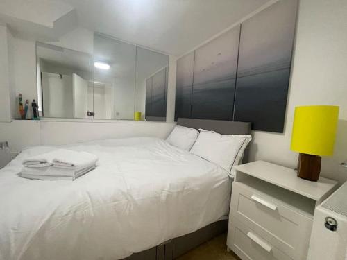 a bedroom with a white bed and a yellow lamp at Stylish flat next to Tower of London and SKD marina in London