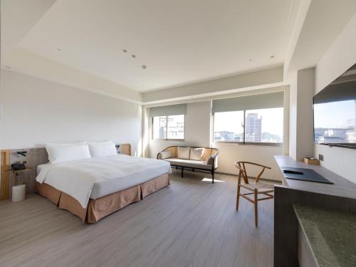 a hotel room with a bed and a desk and windows at Dahu Park Hotel in Taipei