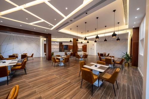 AlRayah Hotel في جازان: غرفة طعام مع طاولات وكراسي في مطعم
