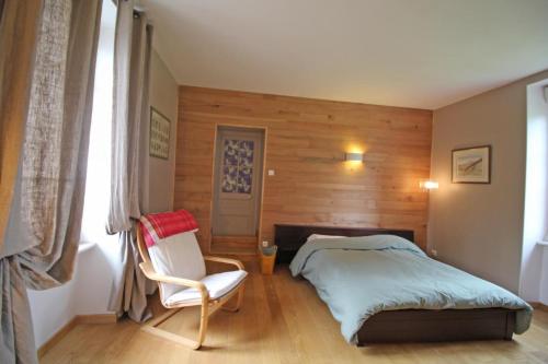 um quarto com uma cama, uma cadeira e uma janela em Le gueraudier em Glandon