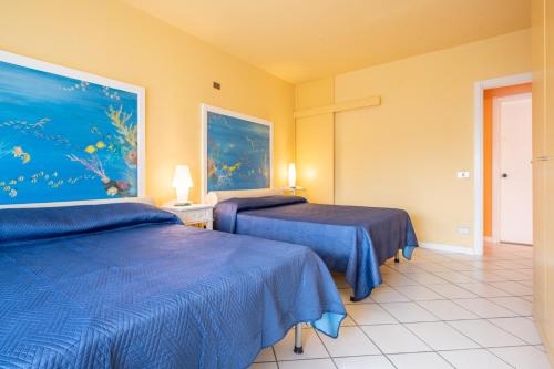 Cette chambre comprend deux lits et un tableau mural. dans l'établissement 100 metri dal mare, à Lido di Camaiore