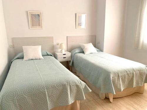ein Schlafzimmer mit 2 Betten und einem Tisch mit einer Lampe in der Unterkunft Apartamentos Pagán in Santiago de la Ribera