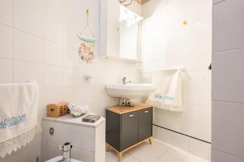 La salle de bains blanche est pourvue d'un lavabo et de toilettes. dans l'établissement 100 metri dal mare, à Lido di Camaiore