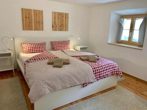 1 dormitorio con 1 cama con manta roja y blanca en Grosszügige Komfort FEWO - ENGADIN HOLIDAYS, en Guarda