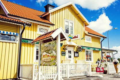 a yellow building with a white fence in front of it at Huset Lisa - SWEEDS Loftahammar in Loftahammar
