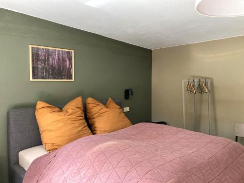 een slaapkamer met een roze bed met oranje kussens bij Bungalow 314 in Joachimsthal