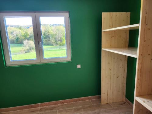 Cette chambre est dotée d'un mur vert et d'une fenêtre. dans l'établissement Gites Jura Sud, à Charchilla