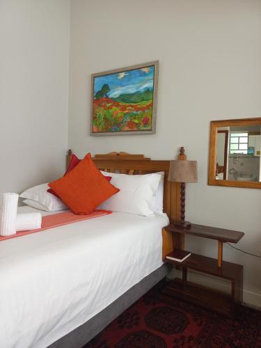 una camera da letto con un letto con lenzuola bianche e cuscini arancioni di Dreamers Guesthouse - NO LOADSHEDDING a King Williamʼs Town