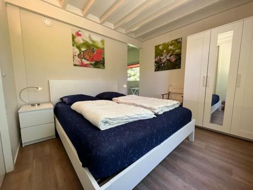 um quarto com uma cama com um cobertor azul em Baken 8 persoons huis loopafstand Grevelingen Noordzee em Scharendijke