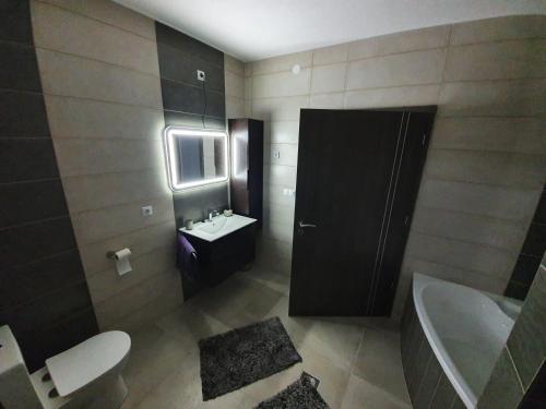 y baño con lavabo, aseo y bañera. en Solymos Apartmanház, en Vámosatya