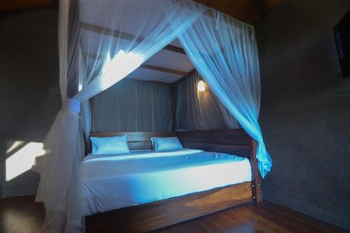a bedroom with a bed with a blue canopy at Ella Camelot in Ella