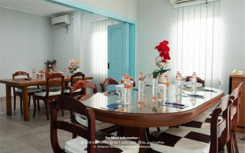 a dining room with tables and chairs and a red flower at de'Govin Hotel in Tjakranegara