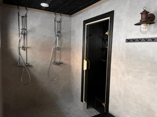 a bathroom with a shower with a black door at Porthos Ski-in Lodge with private hot tub and sauna in Lapland in Pyhätunturi