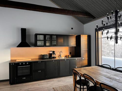 a kitchen with black cabinets and a wooden table at Porthos Ski-in Lodge with private hot tub and sauna in Lapland in Pyhätunturi