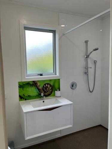 La salle de bains blanche est pourvue d'un lavabo et d'une fenêtre. dans l'établissement Mackenzie Delight, à Twizel