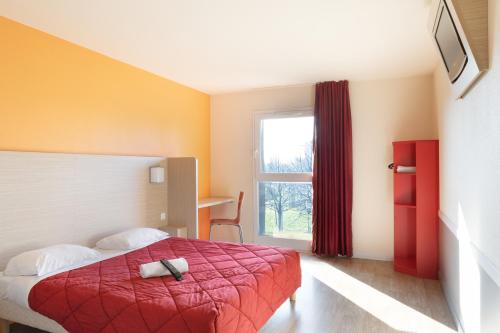 a bedroom with a bed with a red blanket and a window at Premiere Classe Maubeuge in Feignies