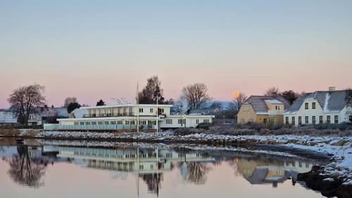 a group of white buildings next to a river at Hørby Færgekro in Holbæk