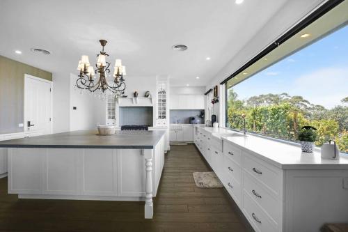 eine Küche mit weißen Schränken und einem großen Fenster in der Unterkunft Luxury & plush lifestyle 5 Bedroom house in Mt Eliza in Mount Eliza