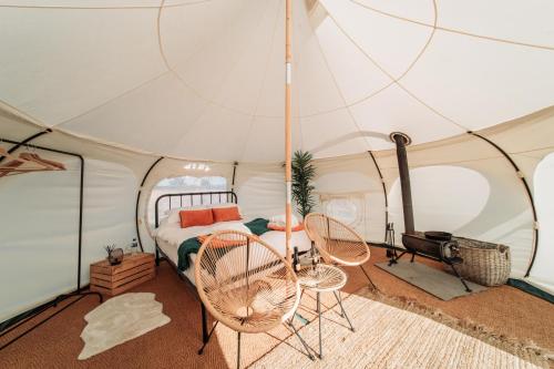 a bedroom with a tent with a bed and two chairs at Bamburgh Under Canvas in Bamburgh