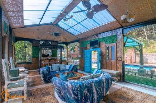 a living room with blue furniture and a glass ceiling at Ekayana Resorts and Agri Tourism, Mulshi in Pune