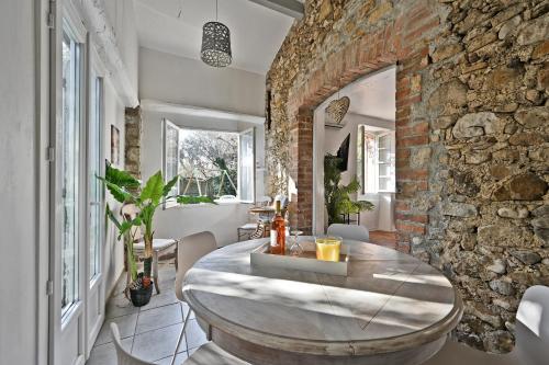 une salle à manger avec un mur en pierre et une table en bois dans l'établissement Mas Demoiselle - Charmante maison 6 personnes, à Tornac