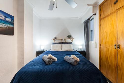 sypialnia z niebieskim łóżkiem i 2 ręcznikami w obiekcie Casa Playa Blanca w mieście Torrevieja