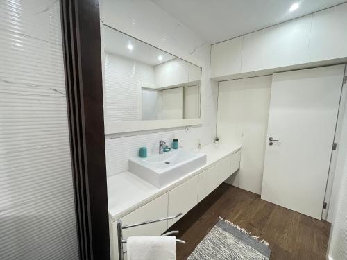 a white bathroom with a sink and a mirror at Casa da Ladeira - Figueira da Foz in Figueira da Foz