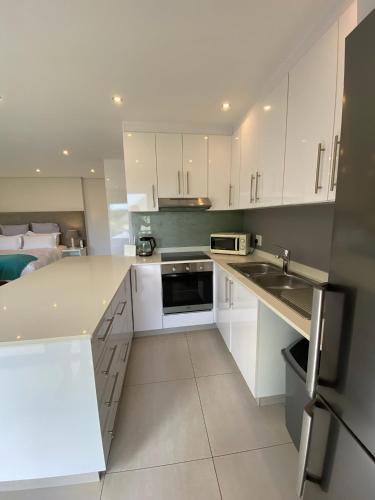 a kitchen with white cabinets and a sink at Luxury Self Catering Studio in Eco Estate in Ballito