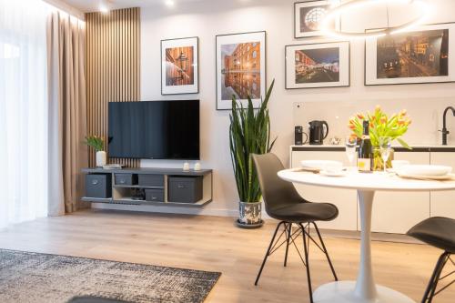 uma sala de estar com uma televisão e uma mesa em Manufaktura Modern Industrial Apartment em Lódź