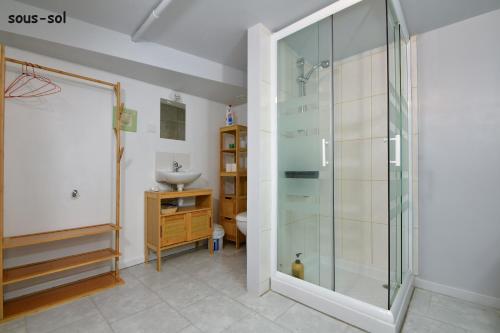 uma casa de banho com uma cabina de duche em vidro e um lavatório. em Les Herbages em Mers-les-Bains
