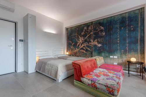 a bedroom with a bed and a couch and a painting at Bologna Tecnopolo Utamaro apartment in Bologna