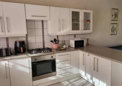 cocina con armarios blancos y fogones en Prestige Self Catering Apartment - Dinokeng Vacinity, en Hammanskraal