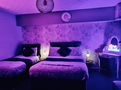 a purple bedroom with two beds and a mirror at The Rose Garden Room - self contained studio in Ballycastle