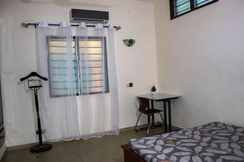 Schlafzimmer mit einem Bett und einem Fenster mit einem Tisch in der Unterkunft Yiri Guest 1 Fidjrossè Plage in Cotonou