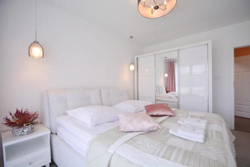 una camera da letto con un letto con lenzuola bianche e un orologio di Apartamenty Bryza-Ułańska 1A12 a Świnoujście