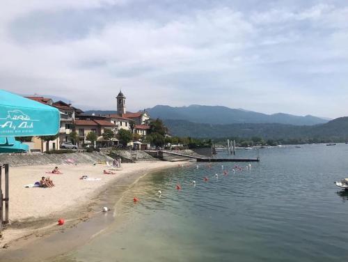a beach with people laying on the sand and the water at Casa Aurora in Baveno