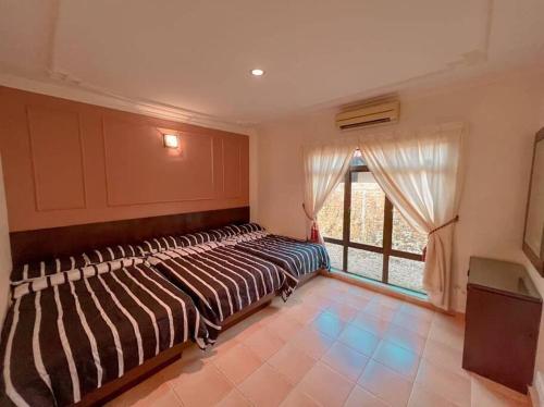 ein Bett in einem Zimmer mit Fenster in der Unterkunft A'Famosa Villa V5 Garden Home Pool Villa Melaka in Kampong Alor Gajah