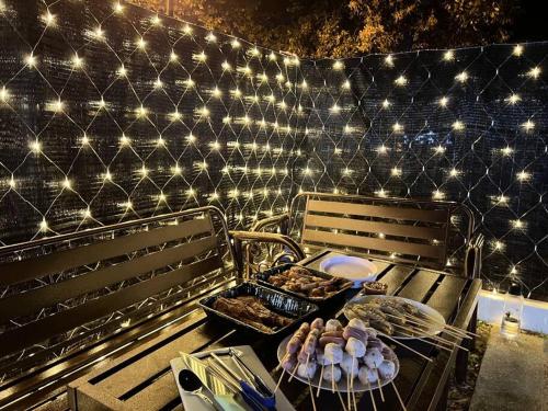 ein Grill mit Essen darauf neben zwei Bänken in der Unterkunft A'Famosa Villa V5 Garden Home Pool Villa Melaka in Kampong Alor Gajah