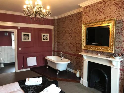 a bathroom with a tub and a tv above a fireplace at The Lady Elizabeth in Sudbury
